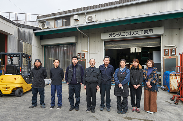 オシタニプレス工業所は、押谷代表（左から4人目）の父が創業した従業員8名の小さな町工場だ。現場担当は6名。経営と事務は代表夫妻が担当している。2018年夏には法人化を予定。